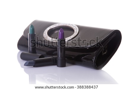 Black handbag clutch and trendy lipsticks, isolated on white background with natural reflection