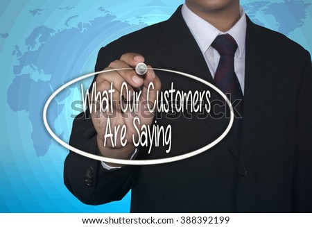 Man Hand writing What Our Customers Are Saying with marker on visual screen. Isolated on sky. Business, technology, internet concept. Stock Photo