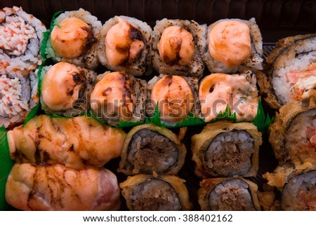 Assortments of sushi: raw, cooked and fried sushi on black rectangle plate