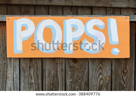 Handmade sign reads "Pops!" at grassroots carnival.