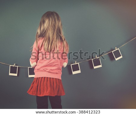 A little child photographer is hanging photos of blank film prints on a clothesline on the wall for a art or creativity concept.