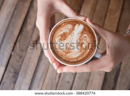 Woman holding hot cup of coffee,Latte Arts,heart sign hand shape