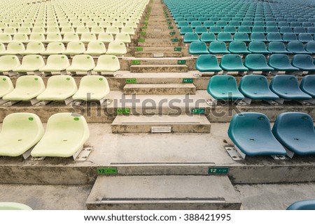 Rows of multilevel empty light and bold green plastic grandstand seats with number at an outdoor sport stadium in Singapore. Seamless pattern of outdoor arena chairs on main stand. Sport background.