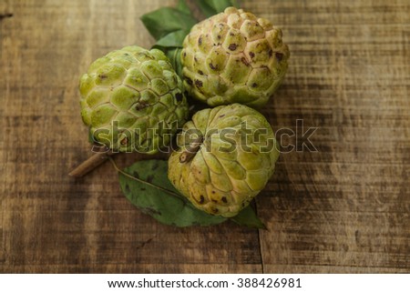 closeup picture of three nice ripe sugar-apples on ripped brown wooden table background