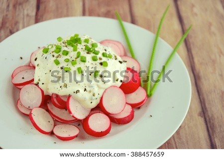Fresh sliced red radish with cream cheese, black pepper and chives on a plate