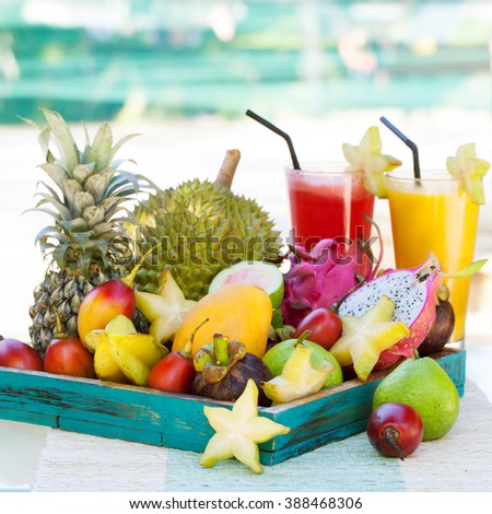 Assortment of tropical exotic fruits with smoothie and fresh juice on a tropical outdoor background