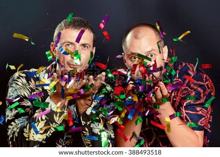 Party time Two friends blowing confetti - celebration, party, fun concept