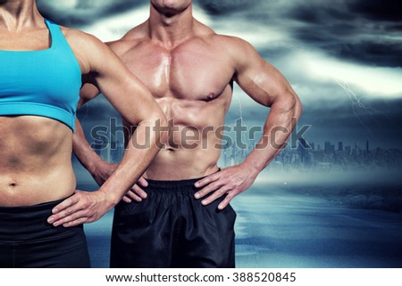 Midsection of muscular woman and man standing with hands on hip against stormy sky with tornado over road
