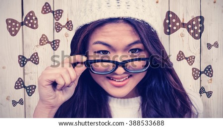 Smiling Asian woman holding eyeglasses against wooden background