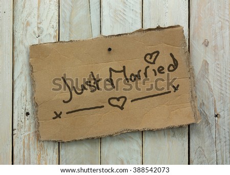 Cardboard sign on a wooden background saying just married