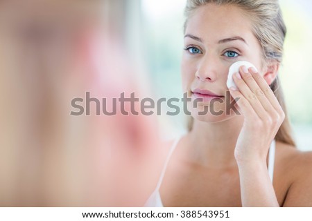 Woman wiping her face with cotton pad in the bathroom Royalty-Free Stock Photo #388543951