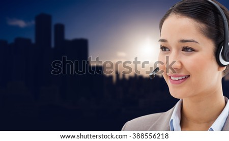 Happy operator posing with a headset against picture of city by sunrise