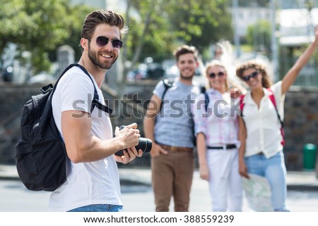 Hip man holding digital camera looking back at the camera