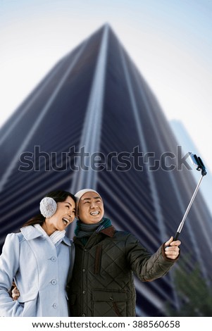 Couples taking funny pictures using smartphone against skyscraper