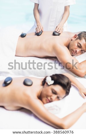 Couple getting a hot stone massage by the pool