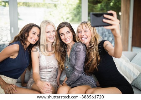Beautiful women smiling and taking selfie with mobile phone at party