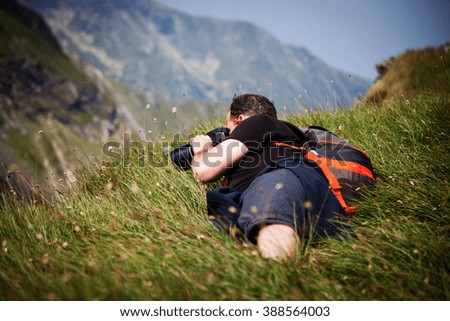 Nature photographer lying in grass and  taking photos in the mountains