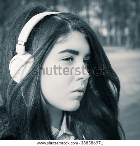 Outdoor close up portrait of a pretty teenage girl with headphones. Black and white