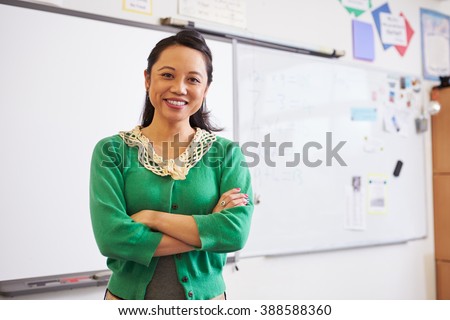 Portrait of confident Asian female teacher in classroom Royalty-Free Stock Photo #388588360