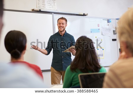 Male teacher listening to students at adult education class Royalty-Free Stock Photo #388588465