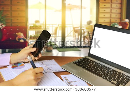 laptop and people holding mobile phone with blur image of people in coffee shop background