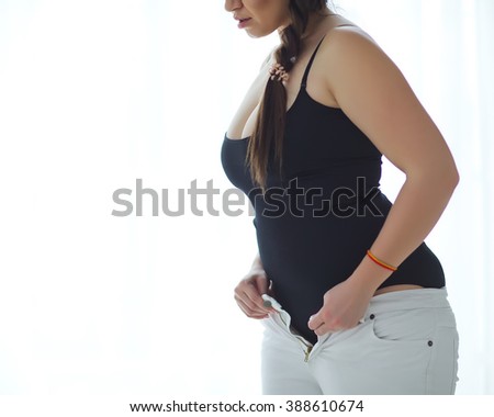 Fat woman trying to wear tight jeans, a concept for obesity issue