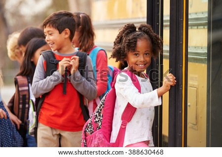 Elementary school girl at the front of the school bus queue Royalty-Free Stock Photo #388630468