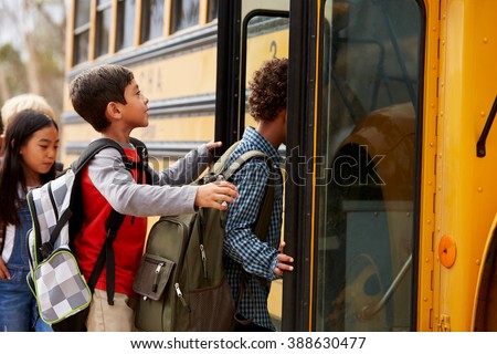 Elementary school kids climbing on to a school bus Royalty-Free Stock Photo #388630477