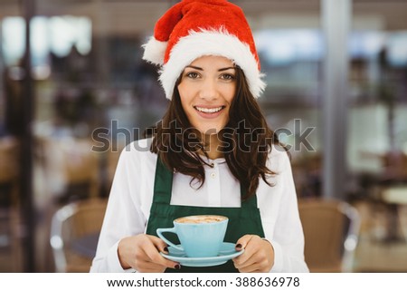 Woman with santa hat holding coffee in cafe