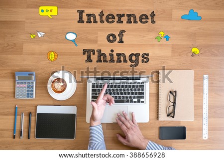 hands at work with financial reports and a laptop with other objects around, coffee,  top view,business man hand working and internet of things (IoT) word diagram as concept