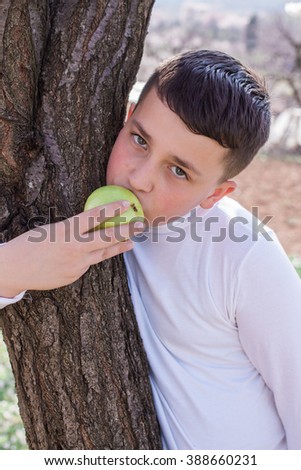 Eating apple among branches of spring tree 