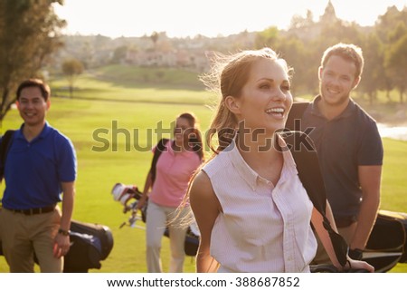 Group Of Golfers Walking Along Fairway Carrying Golf Bags Royalty-Free Stock Photo #388687852