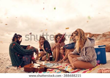 Happy friends partying on the beach with drinks and confetti. Happy young people having fun at beach party, celebrating with confetti. Royalty-Free Stock Photo #388688215