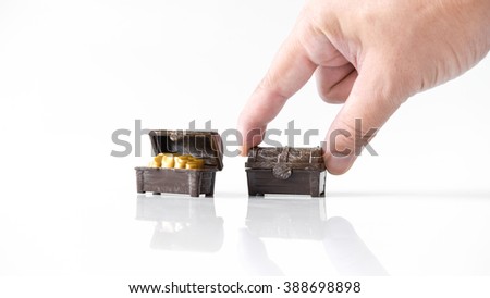 Hand holding or playing with plastic pirate treasure chest with golden coins. Isolated on white background. Slightly de-focused and close-up shot. Copy space.