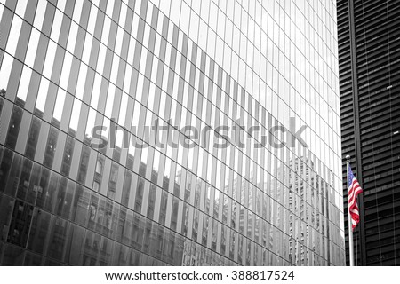 American flag in front of a black and white building glass wall, New York, USA.