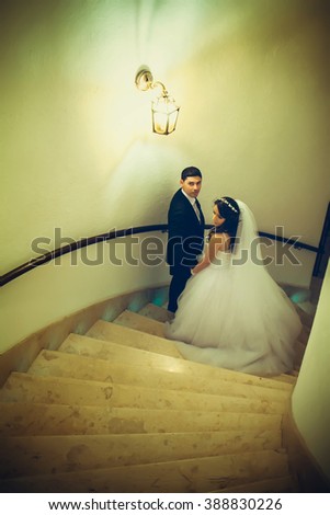 Beautiful couple in a wedding dress standing on the stairs in the hallway of the hotel.