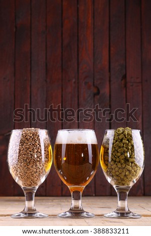 Glasses of beer, malt and hops over a wooden background Royalty-Free Stock Photo #388833211
