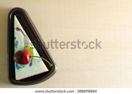 Fancy soap in cake form with cherry on the top on wooden board background