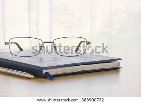 Glasses on a book with on the desk by nature background