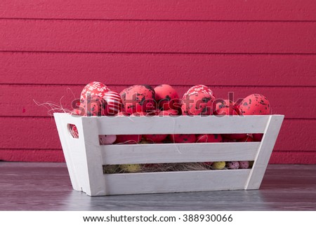 Red Easter eggs in a wooden container on a red background with copy space