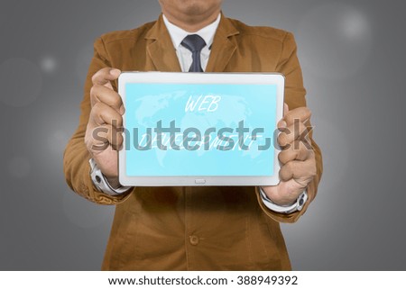 Businessman holding tablet computer with WEB DEVELOPMENT on display.