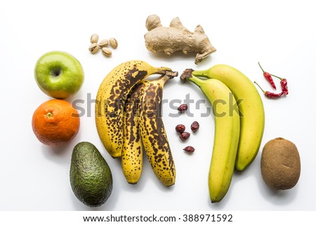 Various fruits flat layed on white background. Bananas, apple, kiwi, pistachio, hip, chilly pepper, orange and ginger. Healthy fruits.