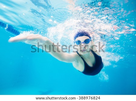 Female swimmer gushing through water in pool Royalty-Free Stock Photo #388976824
