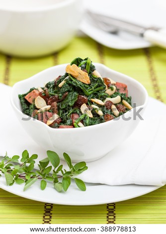 Spinach in a bowl, prepared with garlic, raisins, bacon and pine seeds