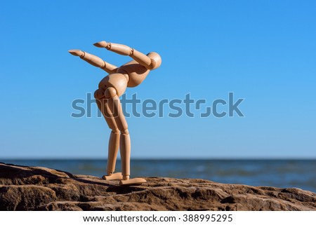 Wooden mannequin stands on the stone and ready to jump in water