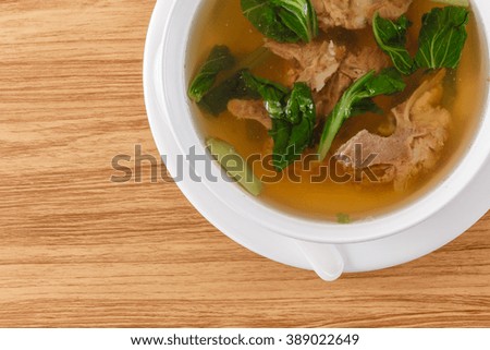 pork bone soup in a white container on a wooden table brown close-up soft focus picture