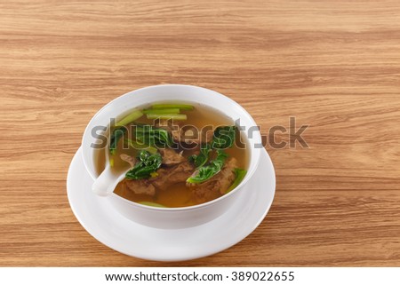 pork bone soup in a white container on a wooden table brown close-up soft focus picture