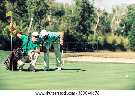 Golf. Golfer reading the green with his caddy Royalty-Free Stock Photo #389040676