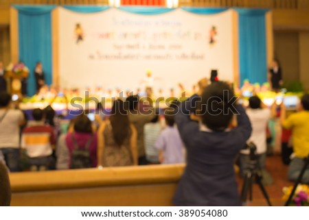 blurred image of backside of cameraboy take photo in the hall ,children on the stage are dancing in school event