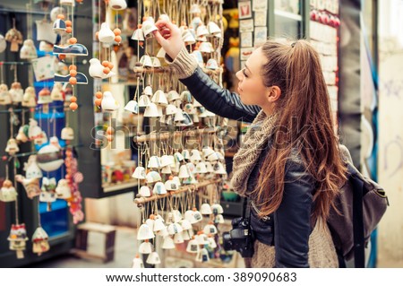 Woman buying souvenirs. Young woman buying souvenirs in gift shop Royalty-Free Stock Photo #389090683